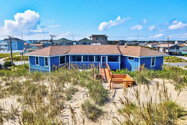 A blue house with a sandy beach in front.