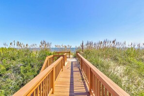 A wooden boardwalk leading to the beach, surrounded by dense vegetation.