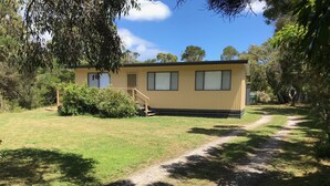 En envåningsbyggnad med ett platt tak, en liten veranda med några trappsteg och en gångväg som leder fram till den.