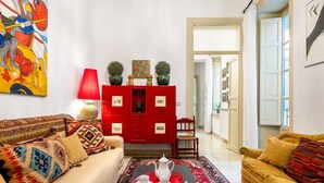 Ein Wohnzimmer mit einem roten Schrank, einem Sofa, einem Couchtisch mit Tablett und einem Gemälde an der Wand.