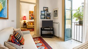 Ein Wohnzimmer mit einer Couch, einem Fernsehmöbel und einem großen Fenster.