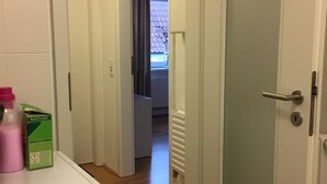 Habitación de hotel con lavadora, radiador y puerta que da a otra habitación.