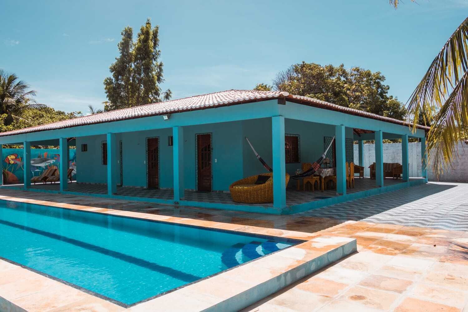 A poolside area with a turquoise building, a swimming pool, and outdoor seating.