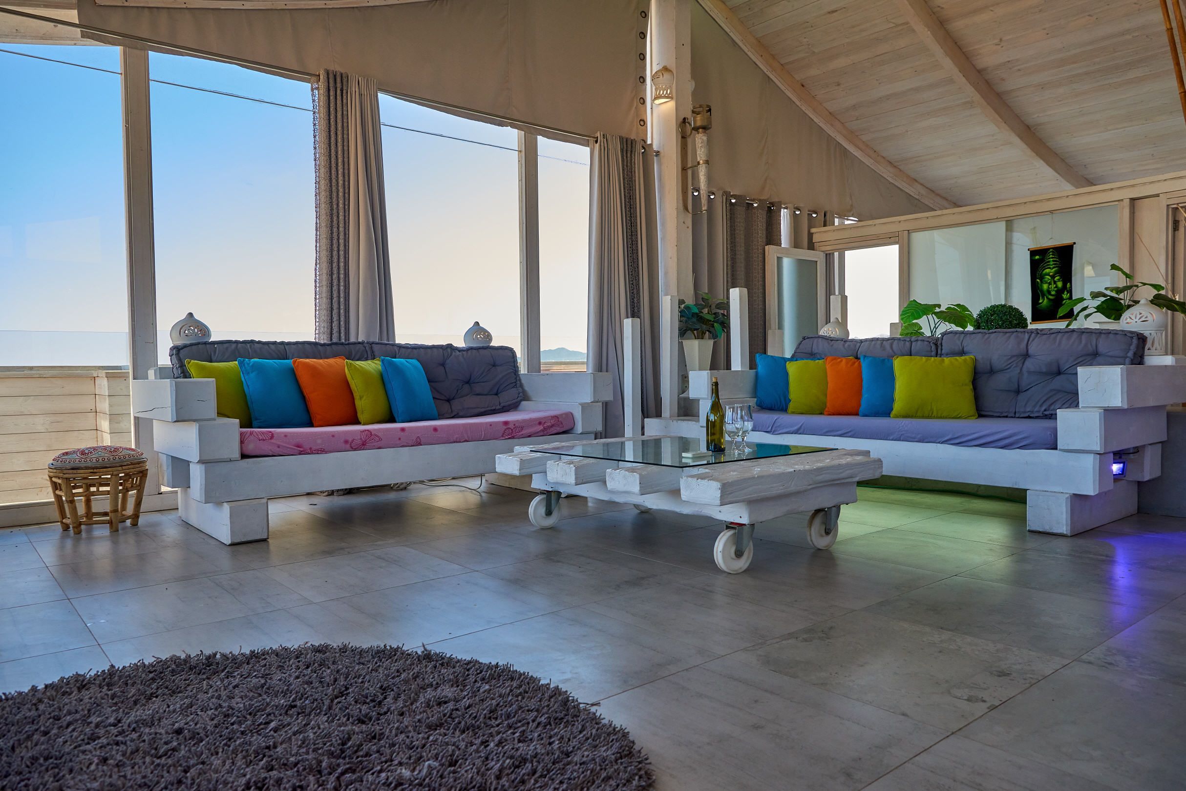 Un salon moderne avec deux canapés, une table basse en verre et une vue sur la mer.