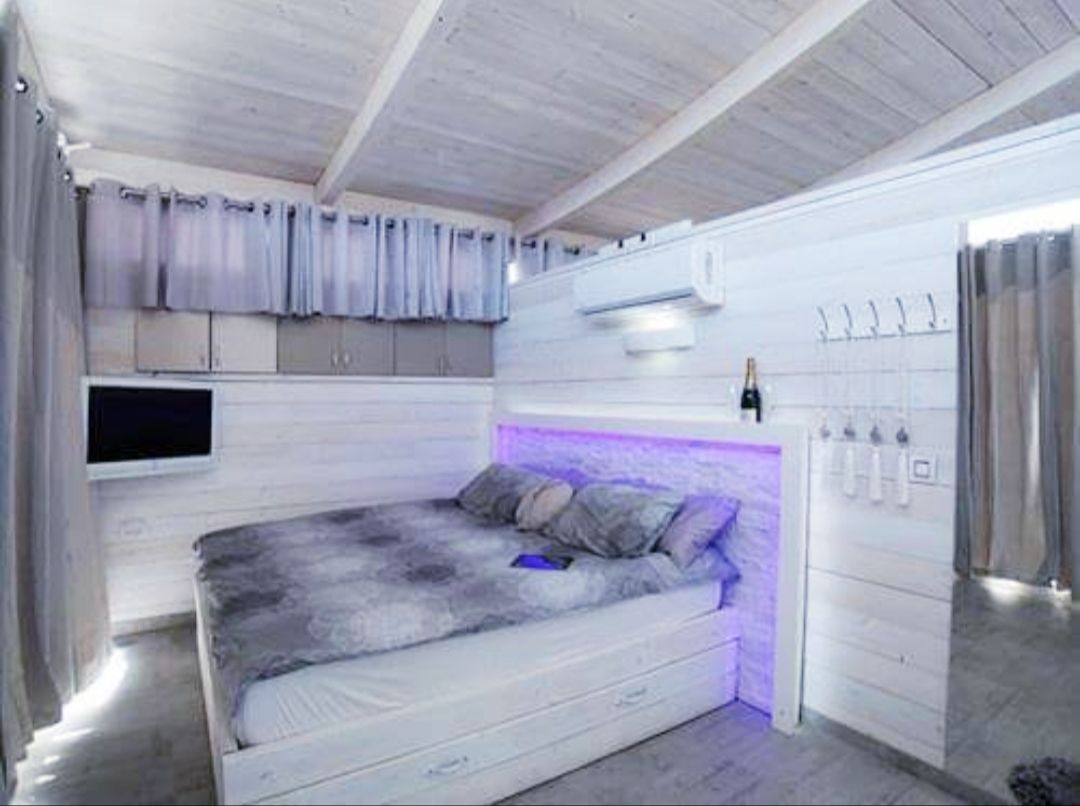A bedroom with a bed, a TV mounted on the wall, and a ceiling fan.