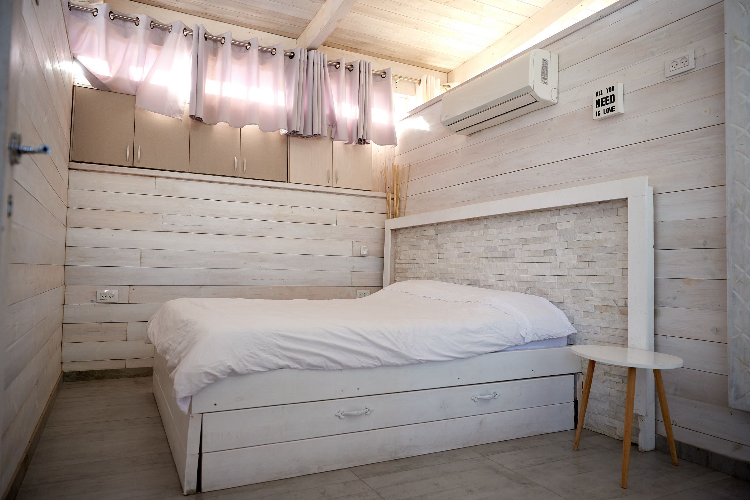 Une chambre à coucher avec un lit, une armoire en bois et une petite table.