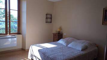 Ein Schlafzimmer mit einem Bett, einem Fenster, einer Heizung, einer Lampe und einem an der Wand befestigten Regal.