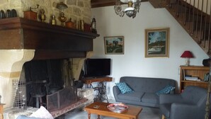A cozy living room with a stone fireplace, a grey sofa, and a wooden coffee table.