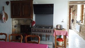 A kitchen with a gas stove, a wooden cabinet, and a red gas cylinder.