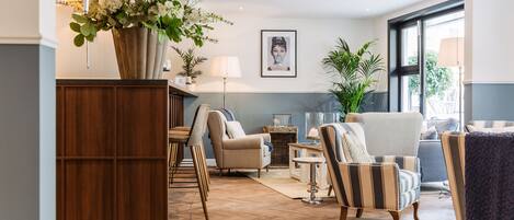 A spacious living room with a wooden floor, a large potted plant, and a sofa set.