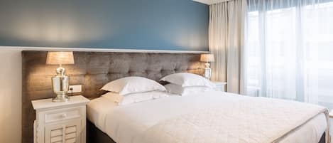 A neatly made bed with a quilted white duvet, a tufted headboard, and two bedside lamps.