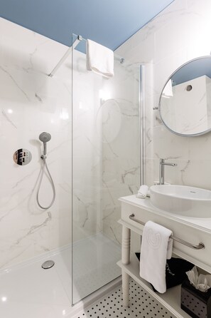 A modern bathroom with a glass-enclosed shower, a white sink, and a large mirror. - Hotel Cocoon (Ostend)