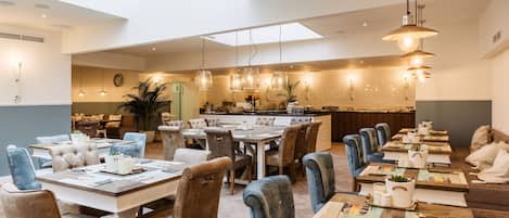 A spacious dining area with multiple tables and chairs, a central island, and pendant lighting.