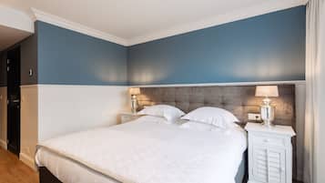 Un dormitorio con una cama grande, dos mesitas de noche con lámparas y un cabecero de madera oscura.
