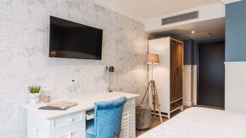 Ein Schlafzimmer mit Bett, Schreibtisch mit Stuhl, Fernseher, Lampe und Kleiderschrank.