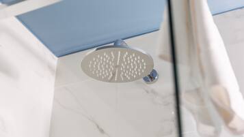 A showerhead with multiple nozzles, a marble floor, and a blue panel in the background.