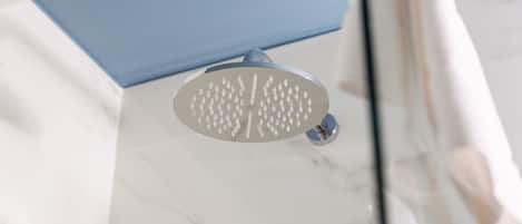 A showerhead with multiple nozzles, a marble floor, and a blue panel in the background.