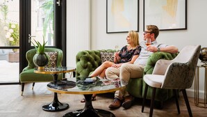 Un salon moderne avec un canapé vert, une table basse en verre et deux tableaux abstraits encadrés accrochés au mur.
