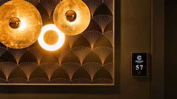 Un mur orné d’un luminaire décoratif et d’une plaque indiquant le numéro de la chambre d’hôtel.
