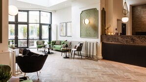 Un hall d’entrée spacieux avec un haut plafond, de grandes fenêtres, un comptoir d’accueil et un mobilier moderne.