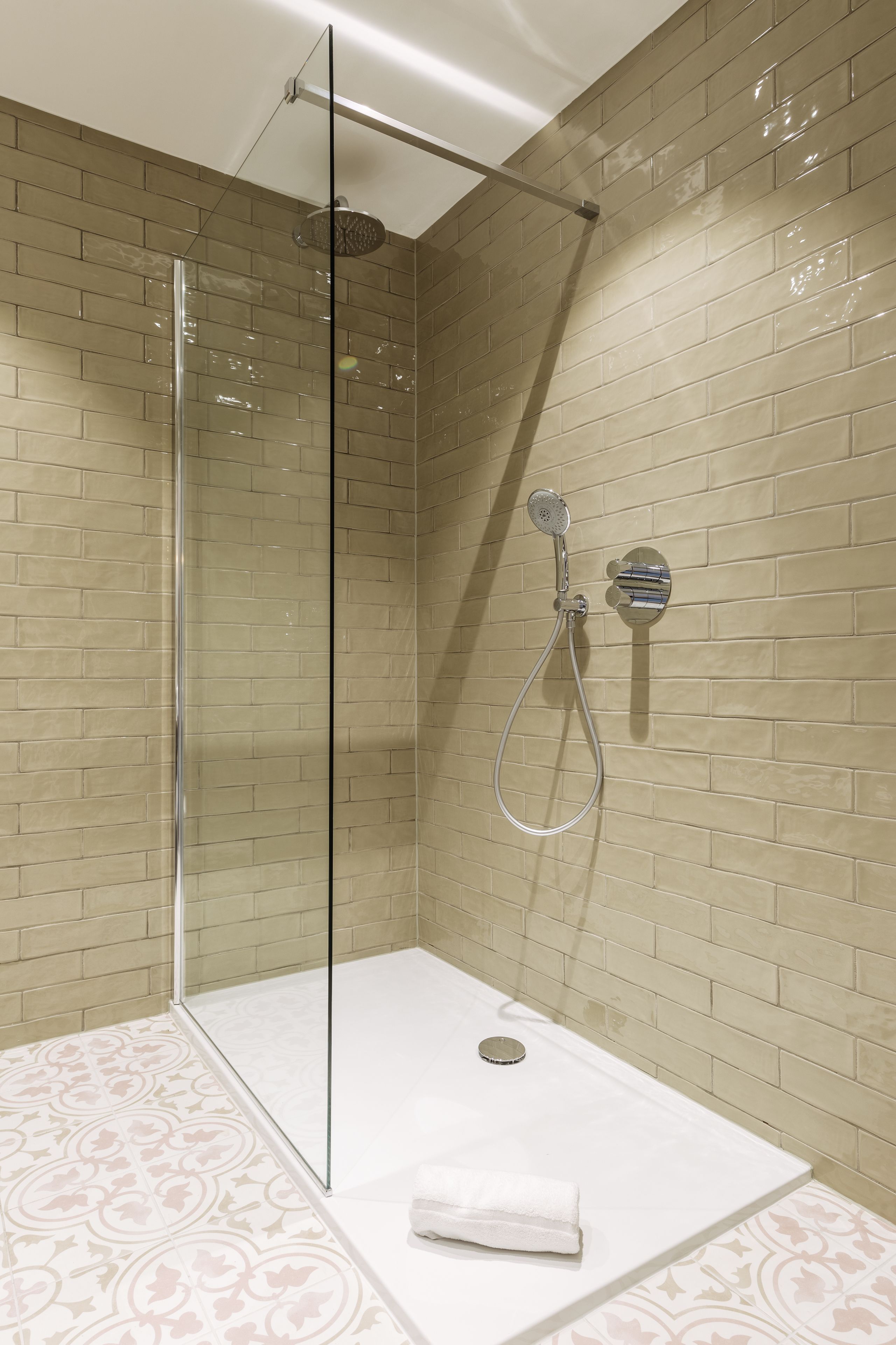 A modern shower area with a glass door, a handheld showerhead, and a wall-mounted control panel.