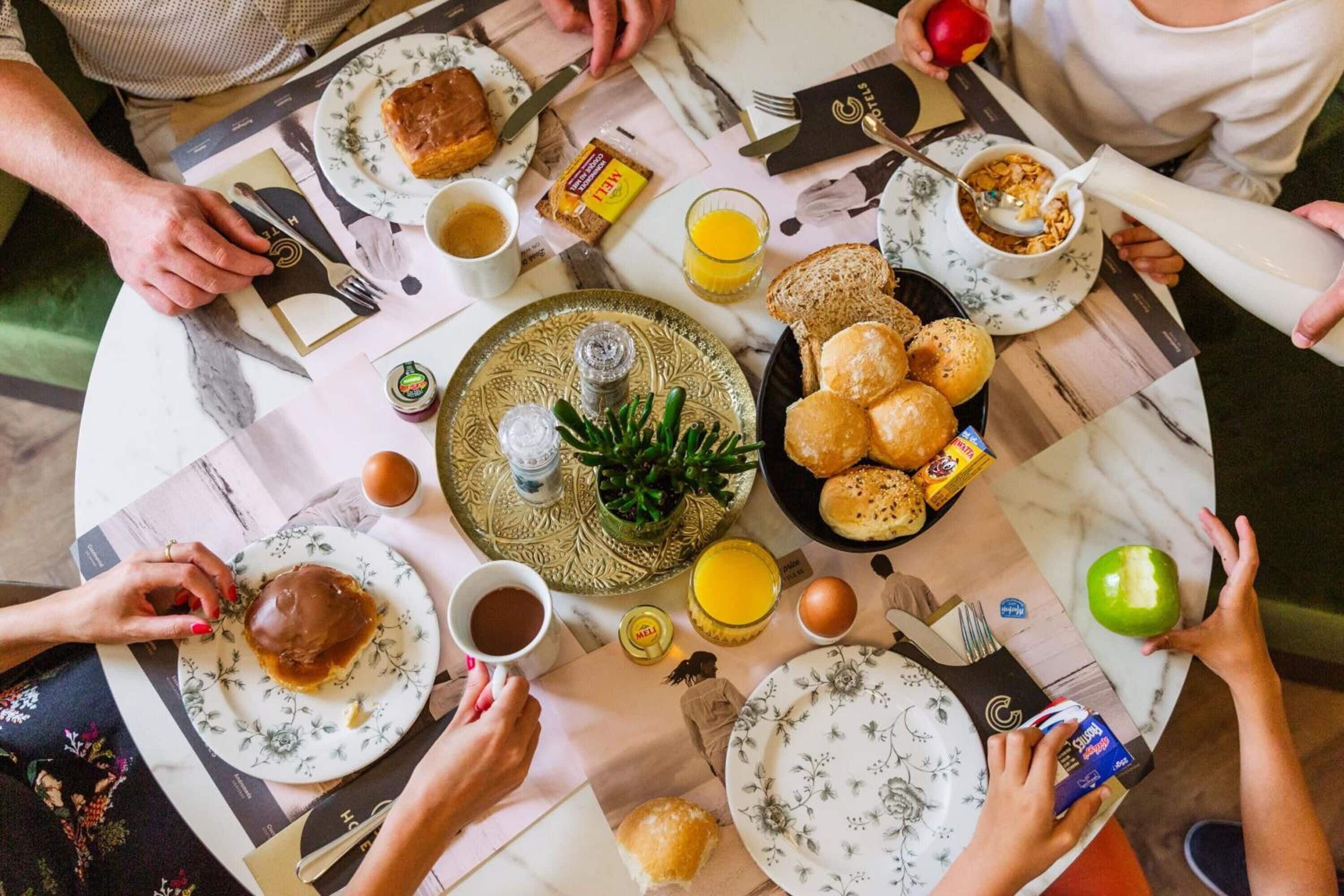 A round dining table with various breakfast items, including bread, eggs, and beverages.