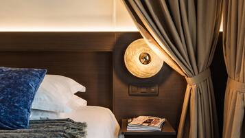 Een hotelkamer met een bed, nachtkastje, lamp en gordijnen.