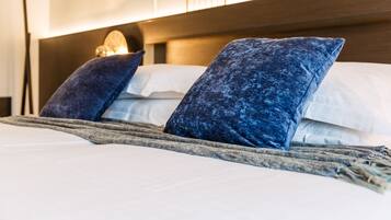 A neatly made bed with a grey blanket and two blue pillows.