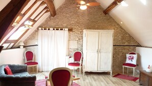 A cozy attic room with a sloped ceiling, wooden beams, a red upholstered chair, a white wardrobe, and a red rug. - Le Plessis-Le Lierre - Loire Valley-Amboise, 18th Century Farmhouse, Pool (Amboise)