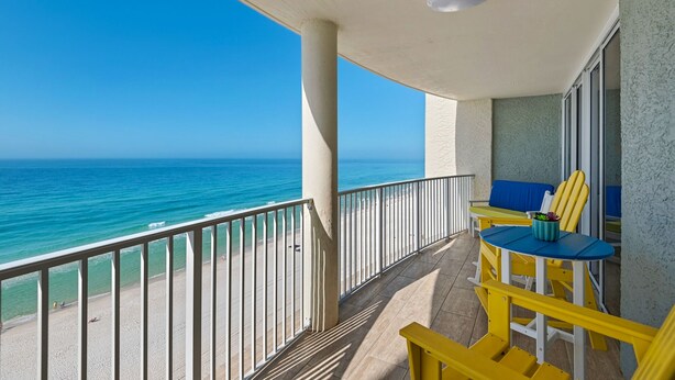 Ein Balkon mit Meerblick, einem Tisch mit Stühlen und einem blauen Kissen.