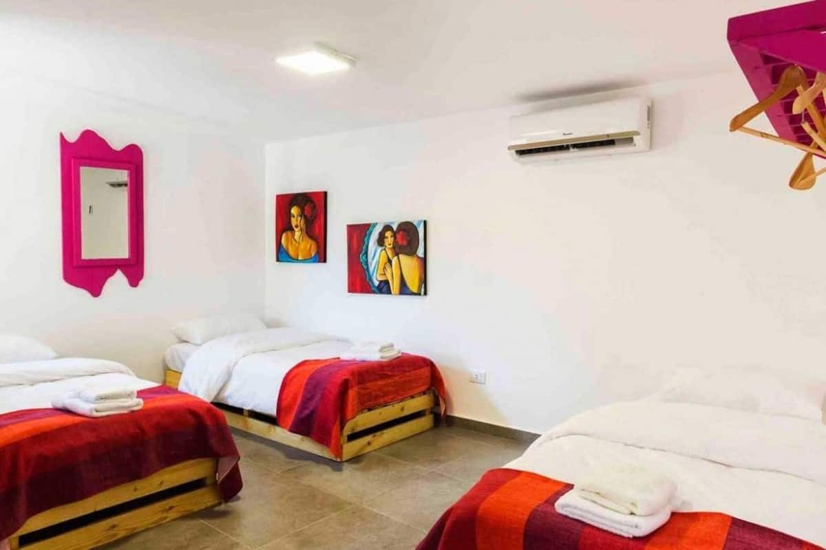A hotel room with two beds, a mirror, and two paintings on the wall.