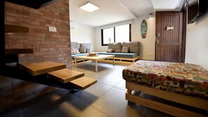 A compact living space with a loft bed, a sofa, a coffee table, and a brick wall. - Old Town Guest Houses (Batroun)