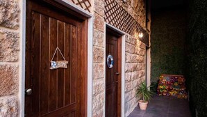 A stone building with two wooden doors, one with a 'WELCOME' sign, and a colorful bench in the background. - Old Town Guest Houses (Batroun)