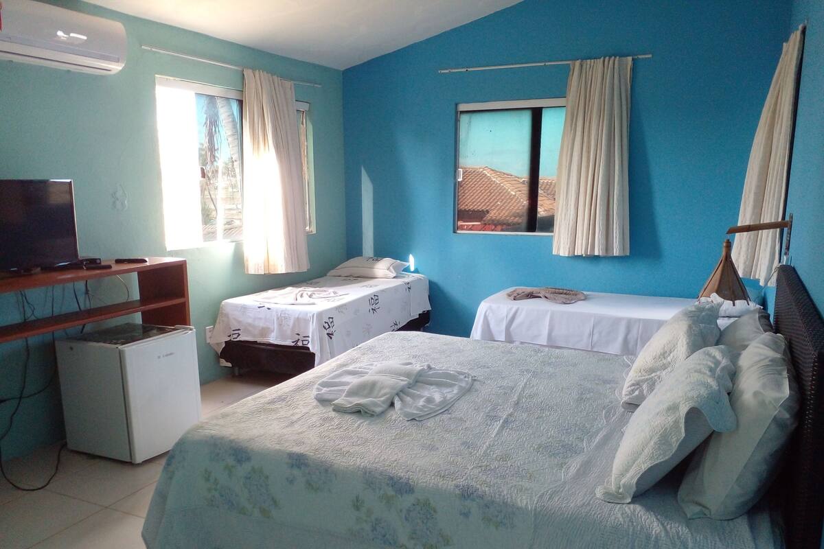 A hotel room with two beds, a television, and a refrigerator.