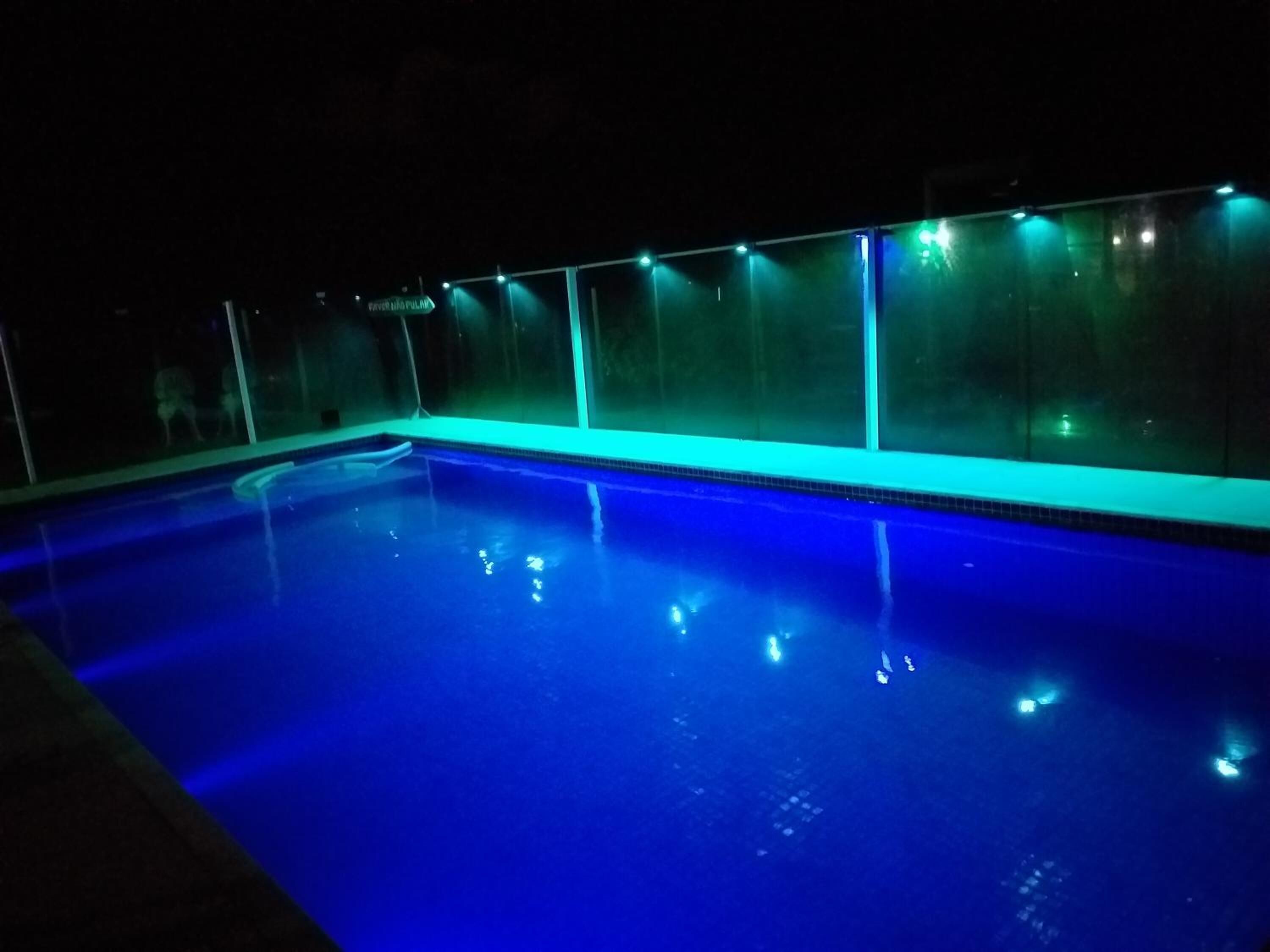 An indoor swimming pool with a blue tint and a glass wall.