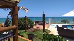Zona de piscina con vista al océano, una pérgola de madera y un espacio de descanso con mesa y sillas.