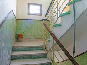 A staircase with green steps and a wooden handrail, leading to a landing with a window and a potted plant. - Casa Mildred (Havana)
