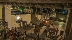 A dimly lit outdoor dining area with wooden furniture and hanging glassware. - Hive 68 - Hotel and Resorts Negombo (Negombo)