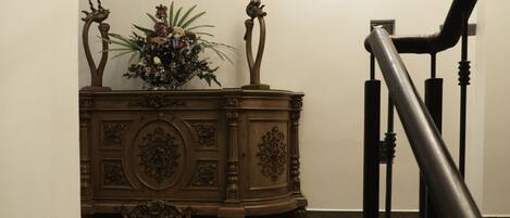 A wooden cabinet with intricate carvings and a floral arrangement on top.