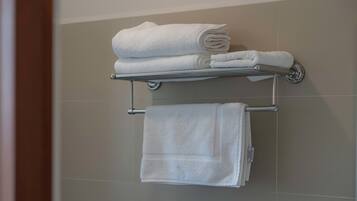 Un baño con un perchero que sostiene dos toallas blancas dobladas y una toalla individual colgando debajo.