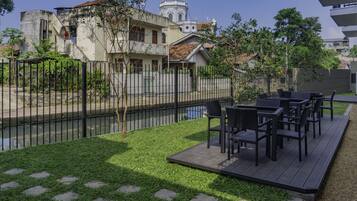 A patio with outdoor furniture, a grassy area, a fence, and a river in the background.