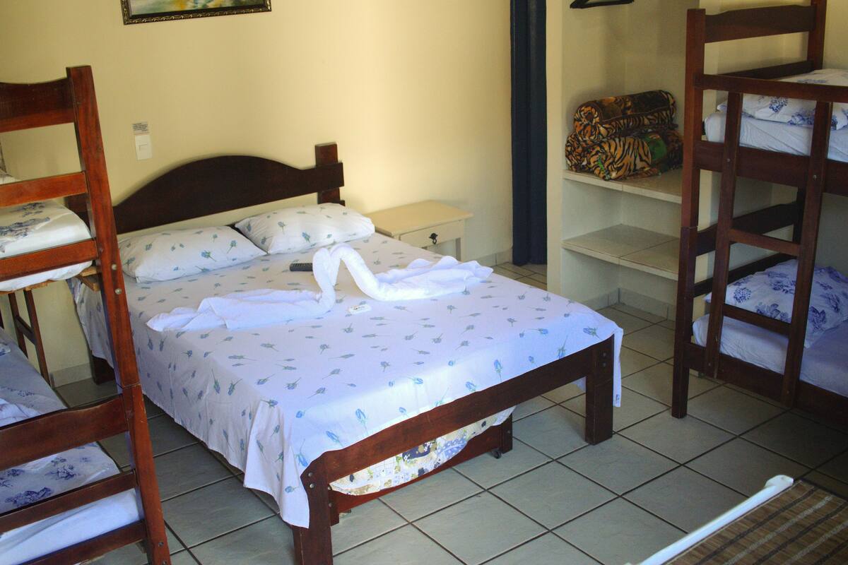 Une chambre avec un lit en bois, une table de chevet et une étagère sur laquelle se trouve un sac à motifs.