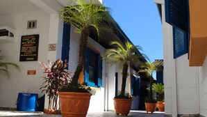 Una calle estrecha con plantas en macetas y un edificio con contraventanas azules.