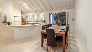Eine moderne Küche mit weißen Schränken, einer zentralen Kochinsel und einem Essbereich mit einem Holztisch und Stühlen.