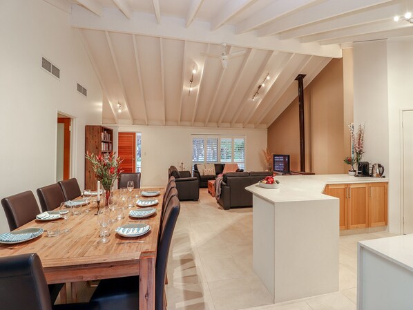 Un vaste espace de vie comprenant une table à manger pour six personnes, un canapé et un coin cuisine doté de meubles en bois.