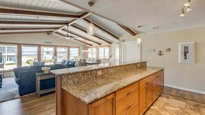 Eine geräumige Küche mit Granit Arbeitsplatte, Holzschränken und einer großen Kochinsel.