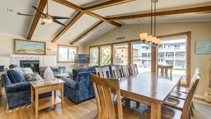 Ein geräumiges Wohnzimmer mit einem großen Esstisch aus Holz, blauen Sofas und einem Deckenventilator.