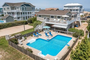 A residential area with a swimming pool, multiple houses, and a beach in the background. - Joy Seas | 265 ft from the beach | Private Pool (Virginia Beach)