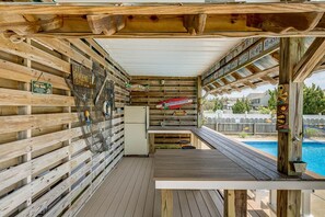 An outdoor wooden deck with a pool, wooden walls with signs, and a small refrigerator. - Joy Seas | 265 ft from the beach | Private Pool (Virginia Beach)