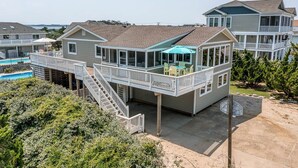 Ein mehrgeschossiges Wohngebäude mit Balkon, Pool und überdachter Terrasse.